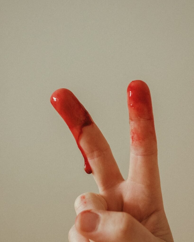 person with red manicure doing peace sign